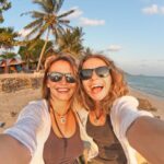 Two happy girlfriends making selfie on the coast of tropical sea