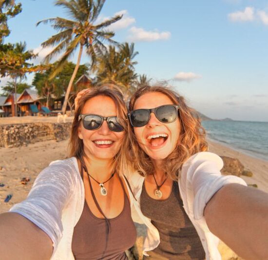 Two happy girlfriends making selfie on the coast of tropical sea